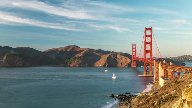 SAN-FRANCISCO, USA - OCTOBER 26, 2024: A serene sailboat crosses the bay while vibrant hills and the iconic Golden Gate Bridge form a stunning backdrop.