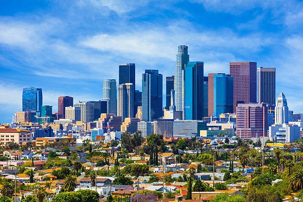 Urban sprawl fills the foreground leading back to the skyscrapers of Los Angeles skyline with cloudscape behind, California